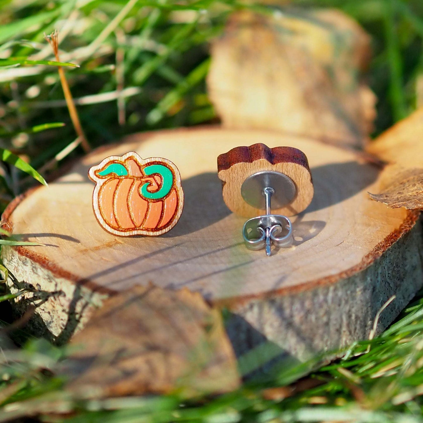 Hand-painted pumpkin stud earrings on cherry wood with surgical steel posts.