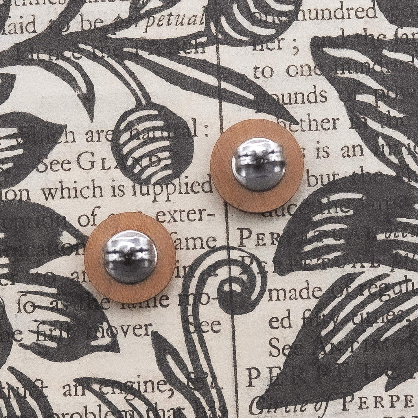 Black and white geometric painted studs made from sustainable cherry wood with surgical steel posts, eco-friendly packaging.