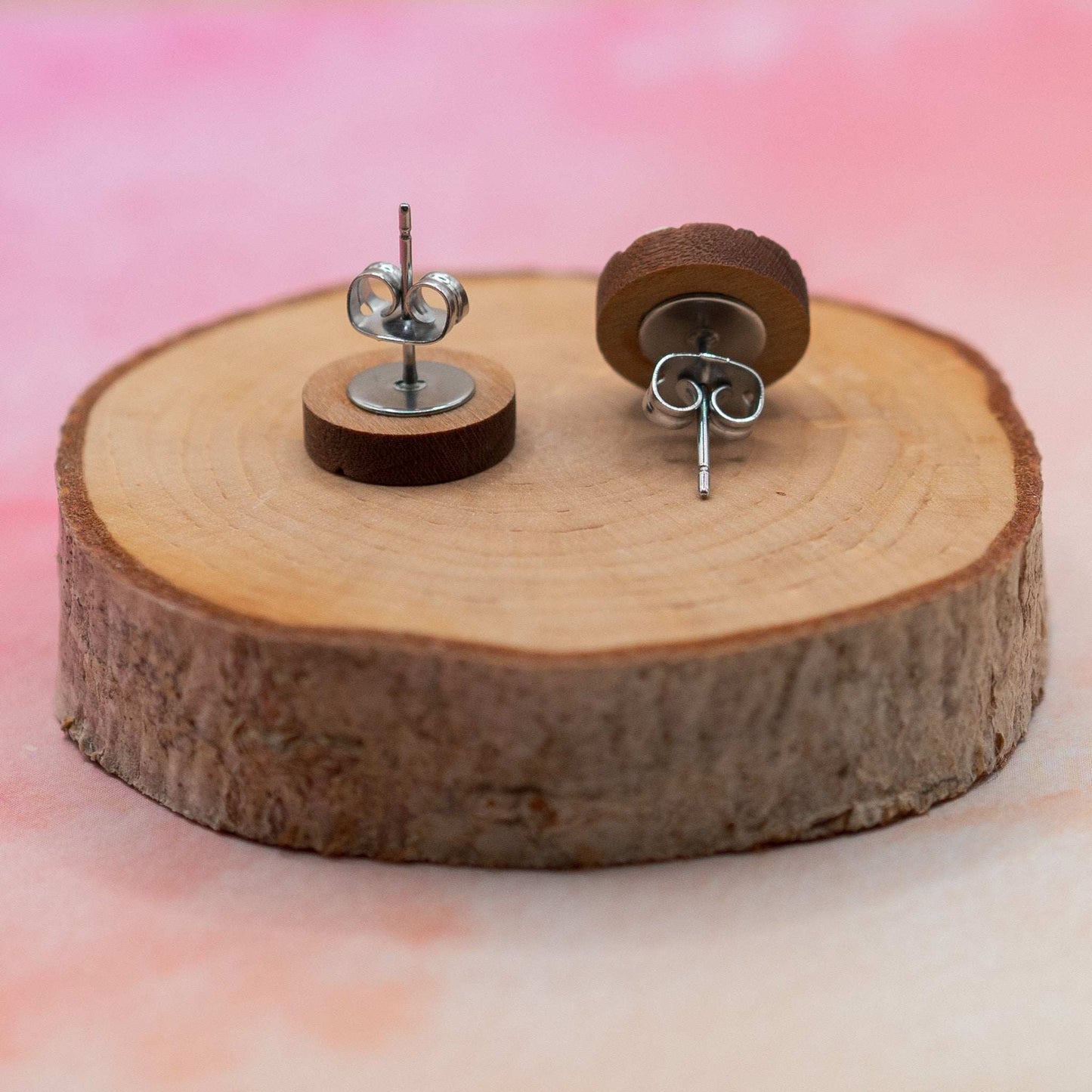 Monochrome geometric painted stud earrings on wooden display with surgical steel backs.