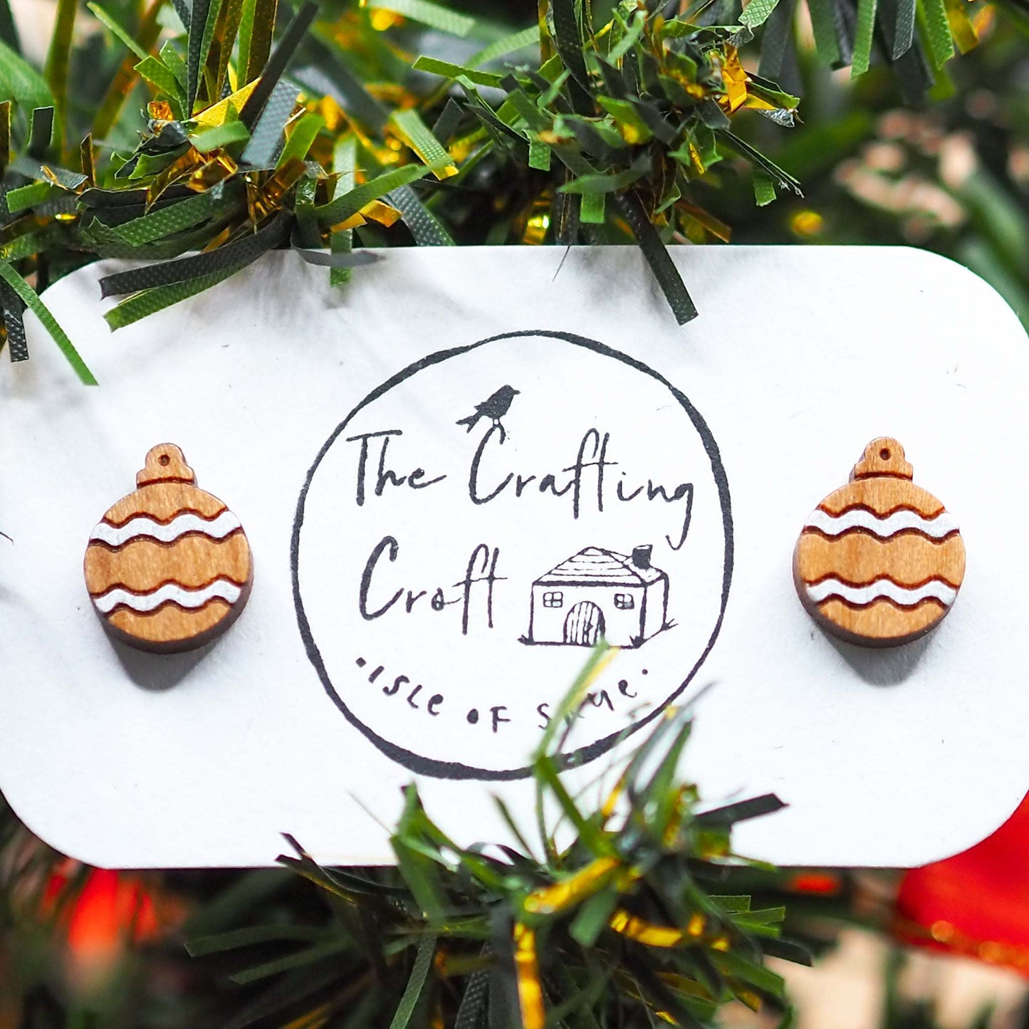 Silver Christmas bauble earrings made of cherry wood with silver pattern on a display card.