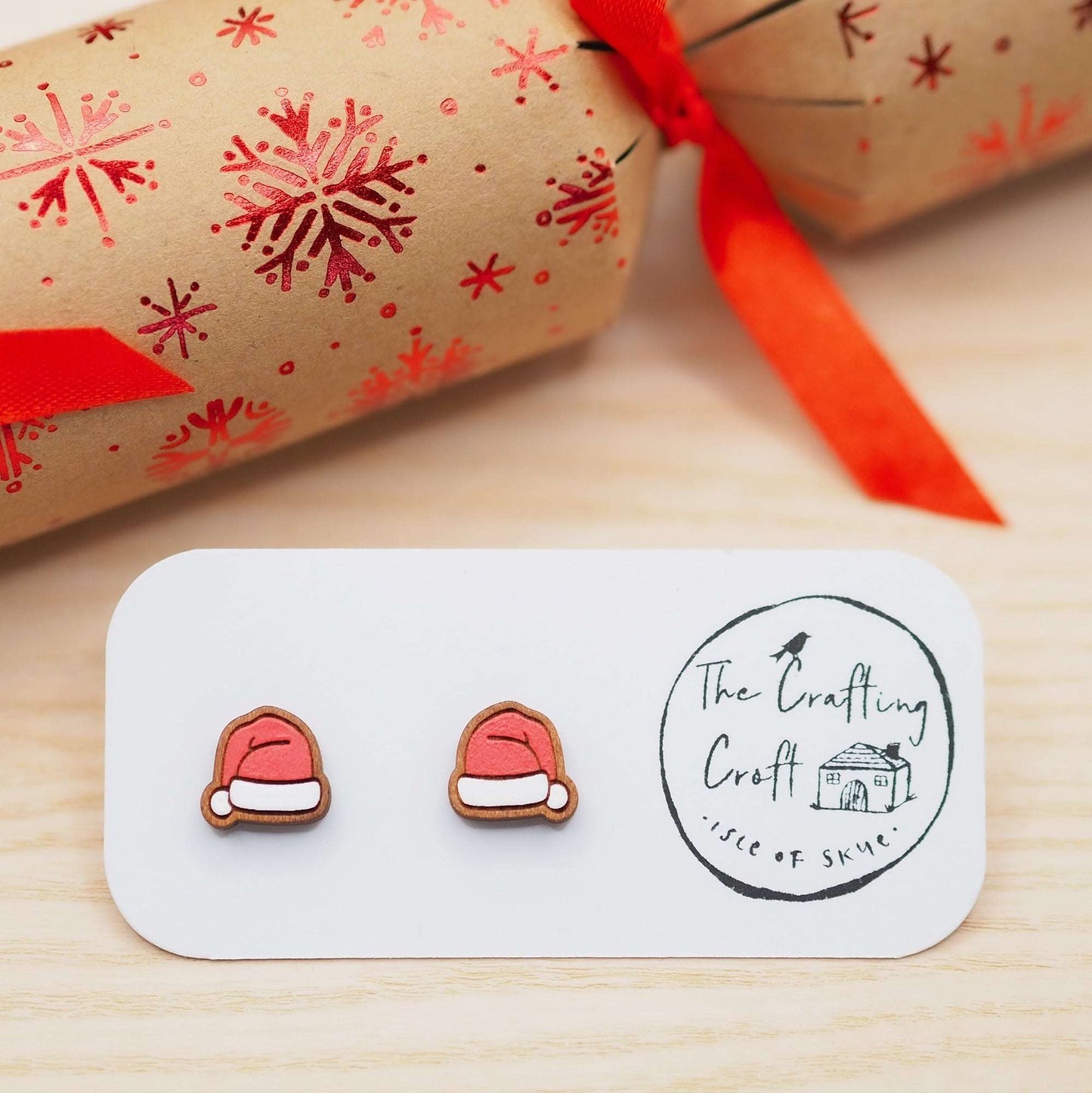 Santa hat studs made from cherry wood with surgical steel posts, displayed in eco-friendly packaging.
