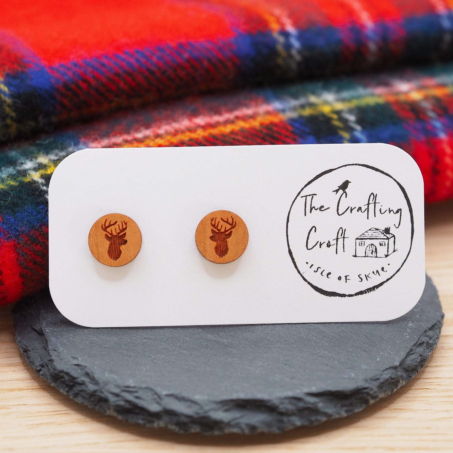 Stag head stud earrings made from cherry wood with engraved design, displayed on a card with a logo.