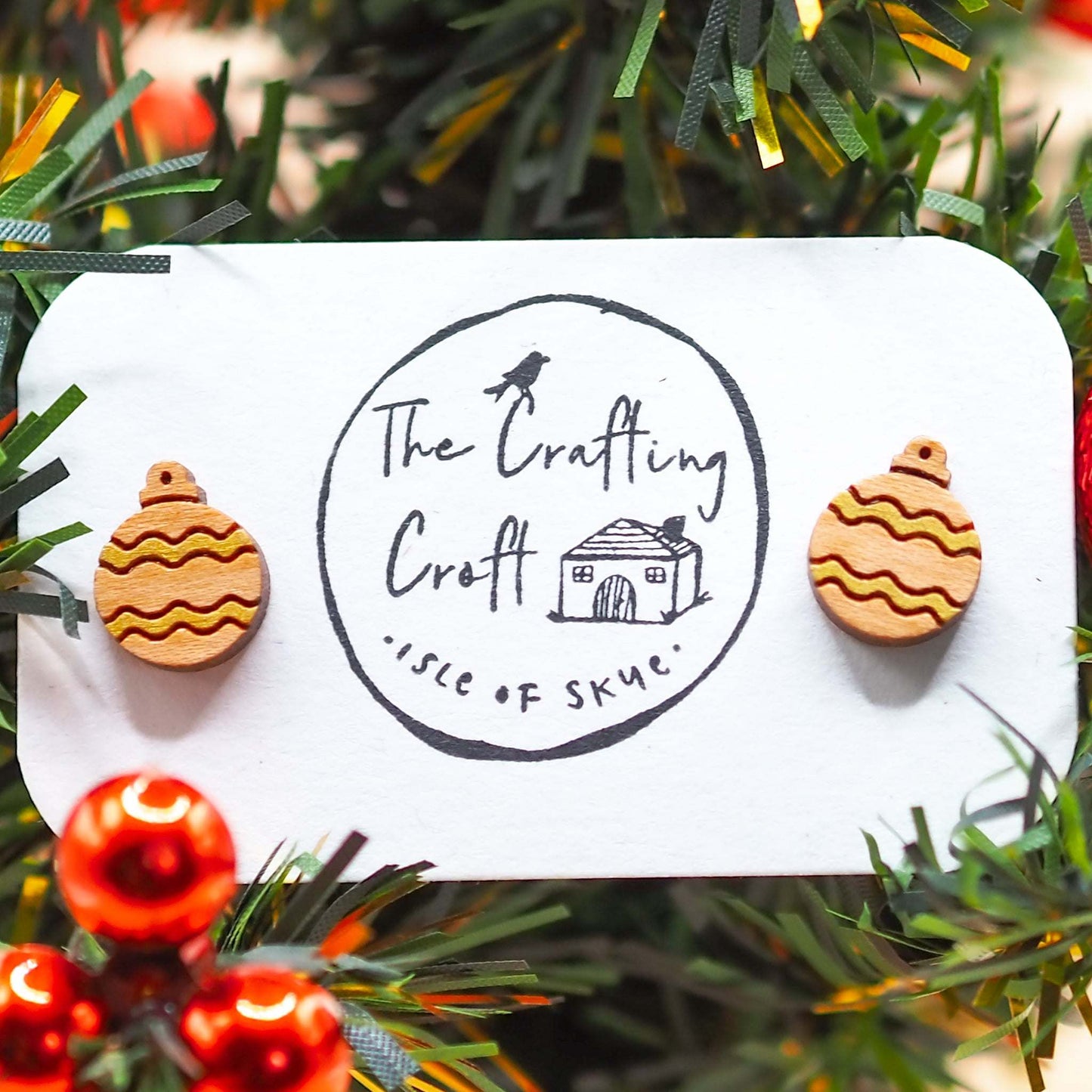 Gold Christmas Bauble earrings on festive display card with tree backdrop.