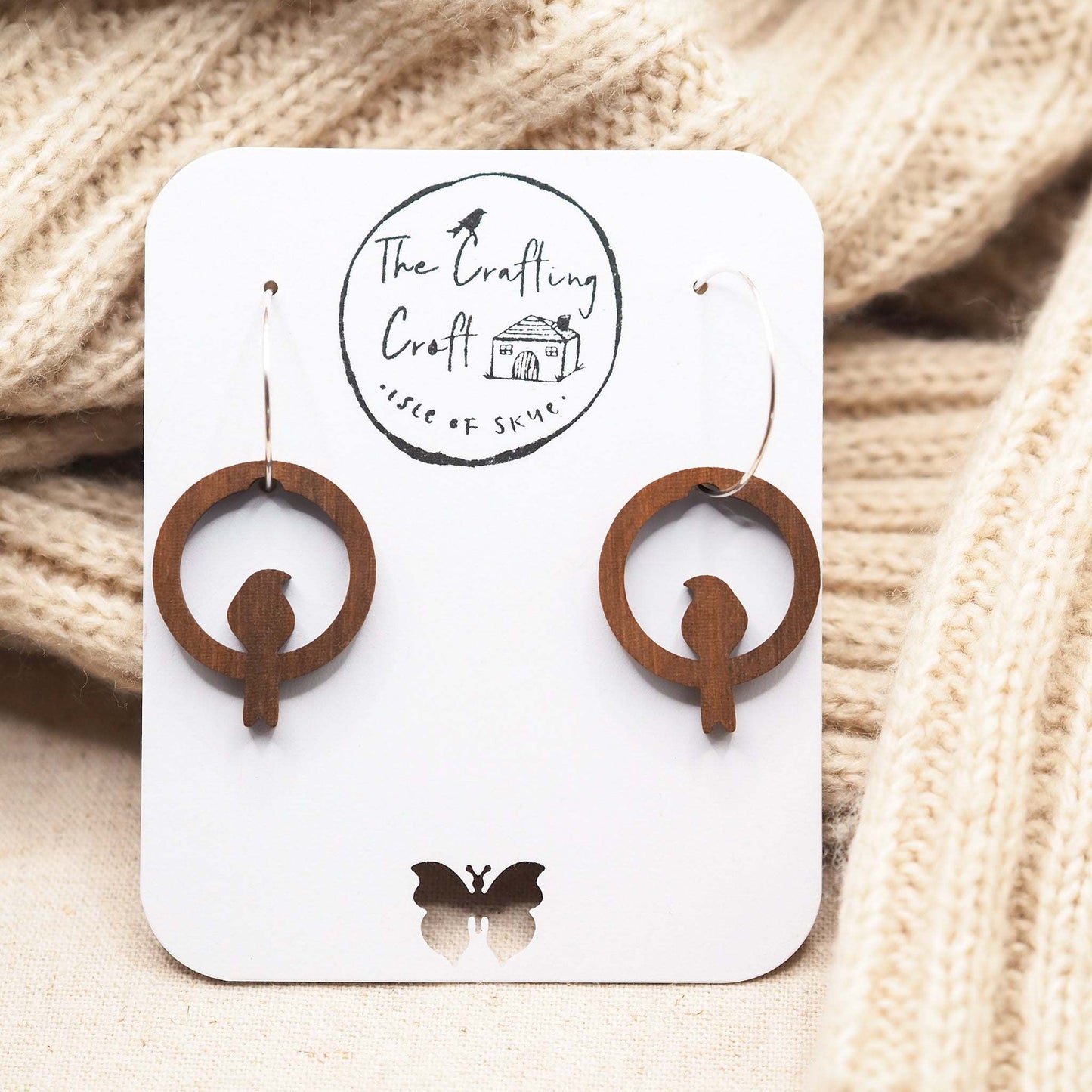 Perching bird hoop earrings made from walnut wood on sterling silver hoops displayed on card.