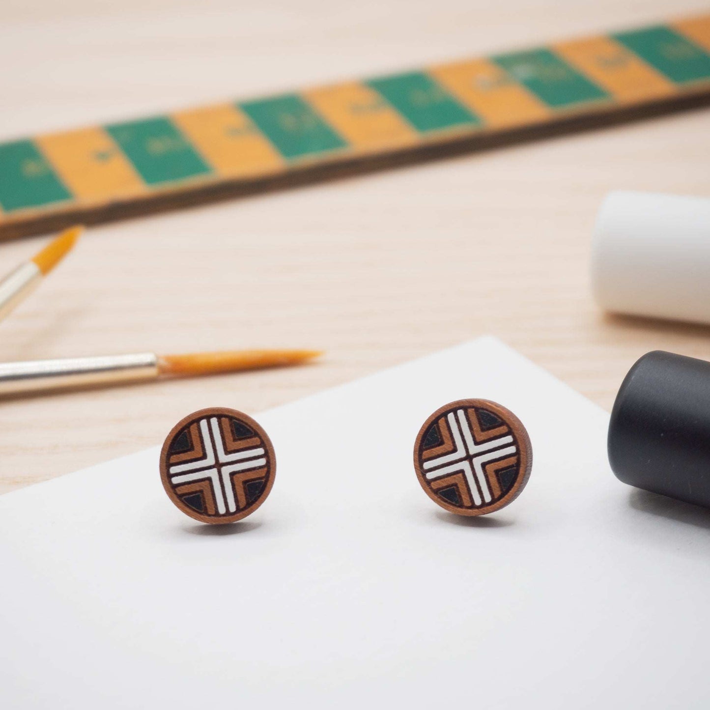 Black and white geometric painted studs on a wooden surface with paintbrushes.