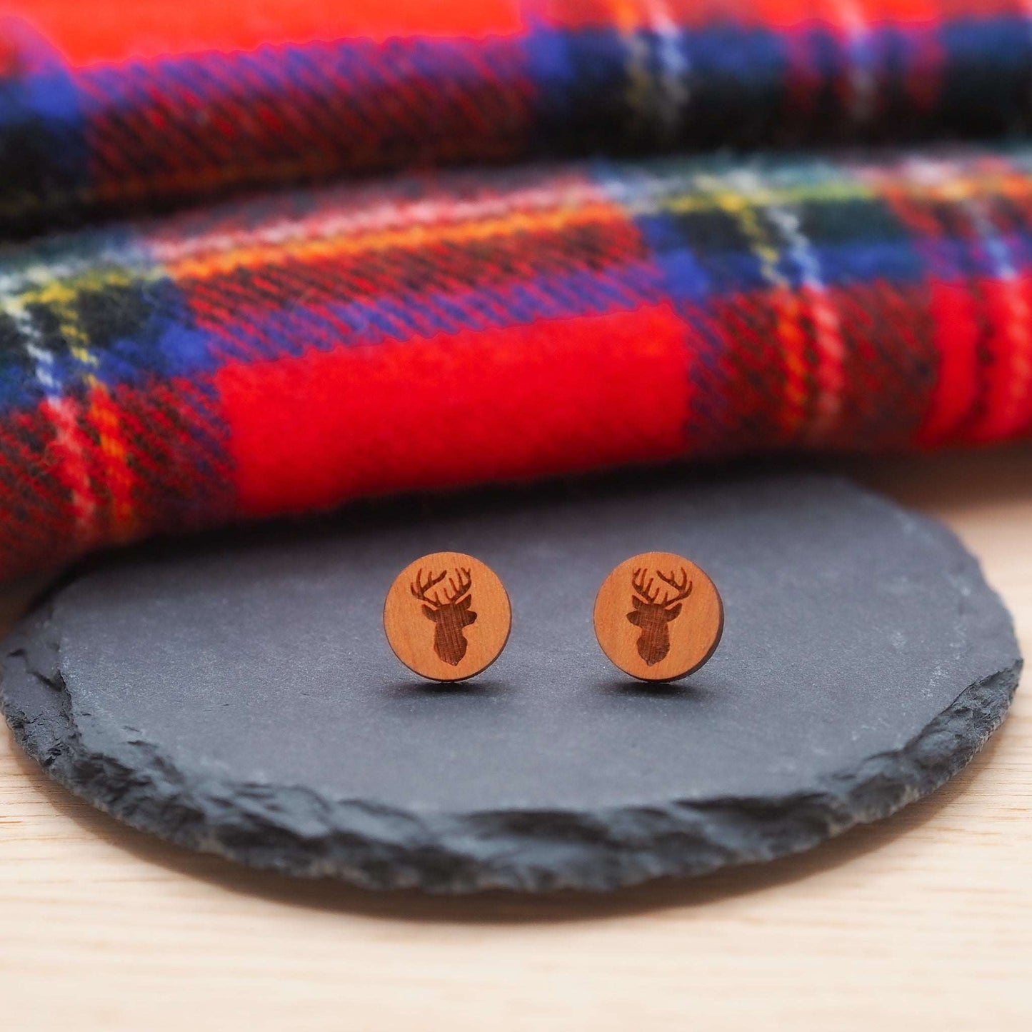 Stag head stud earrings made from laser-cut cherry wood on slate background.