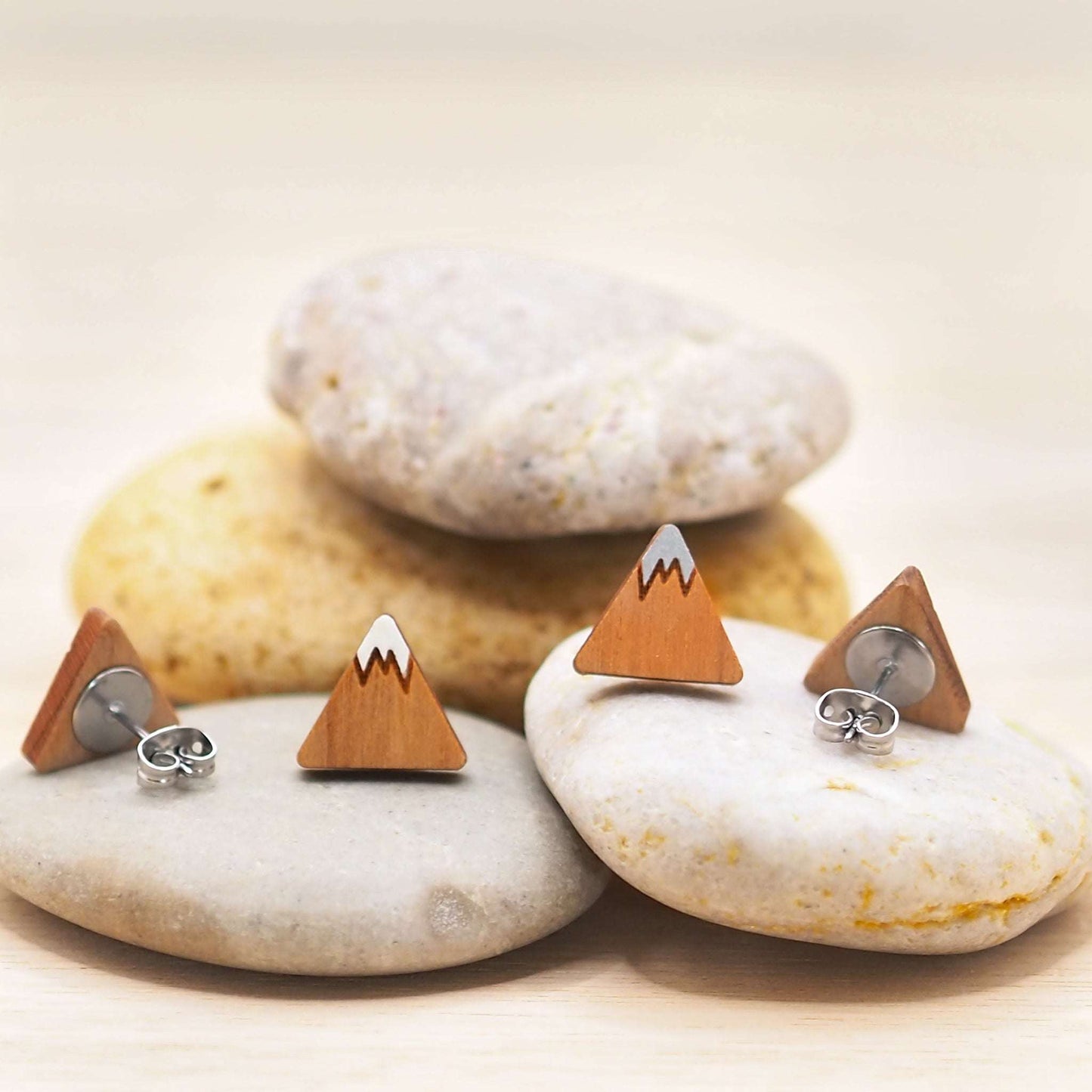 Hand-painted mountain stud earrings made from solid cherry wood with surgical steel backs, displayed on stones.