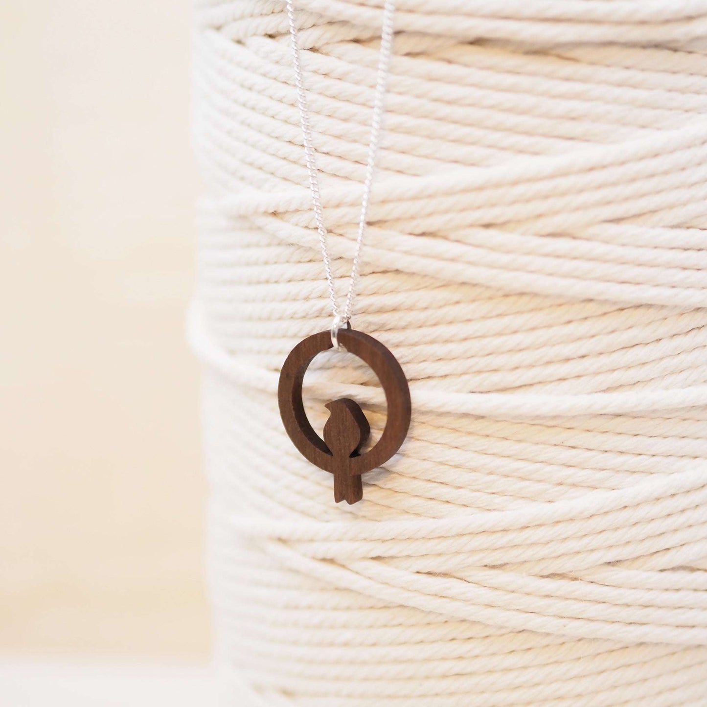 Wooden bird hoop necklace on recycled sterling silver chain, eco-friendly packaging.