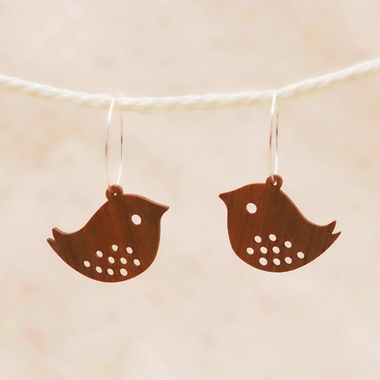 Quirky bird hoop engraved earrings made from walnut wood and sterling silver hoops, displayed against a neutral background.
