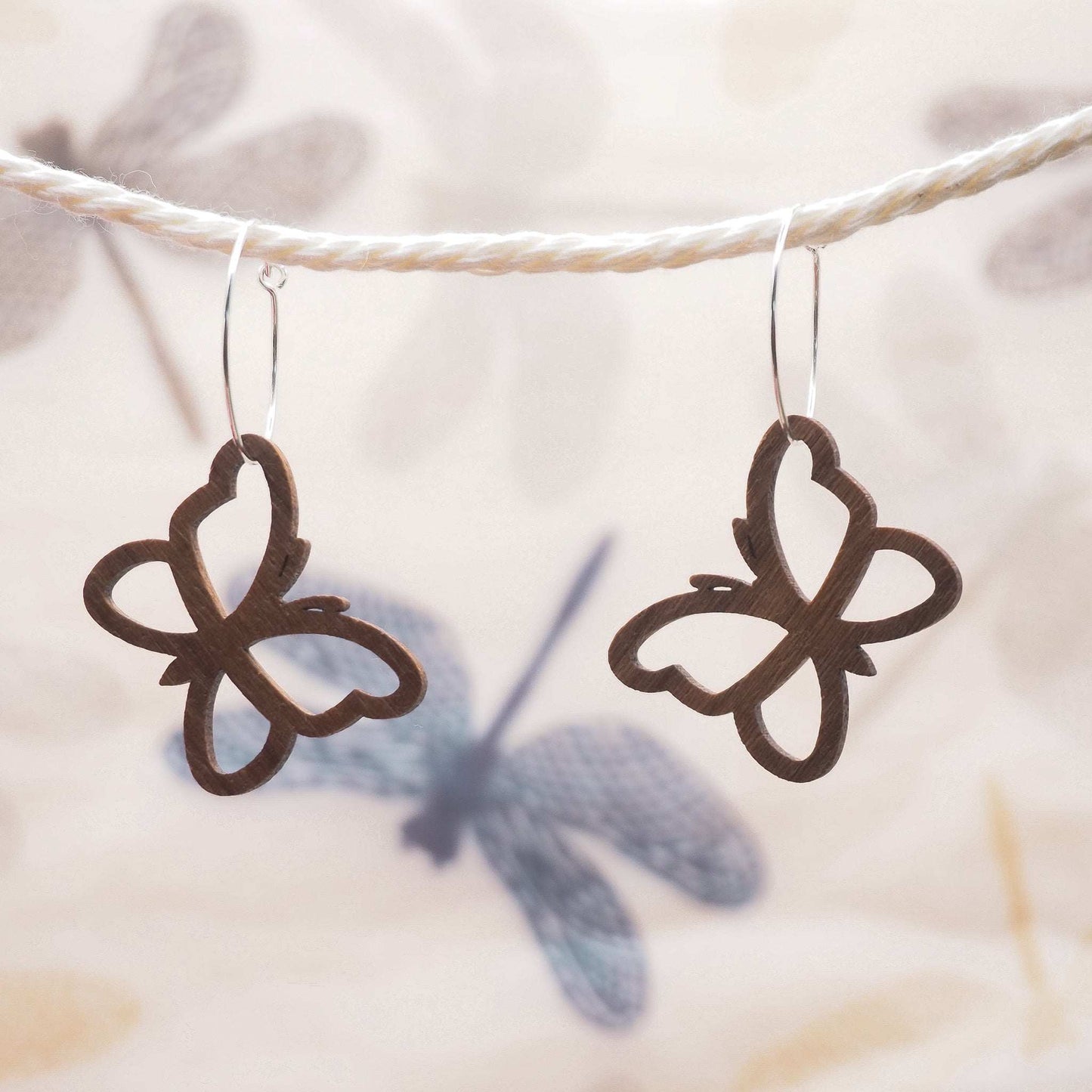 Butterfly outline hoop earrings made from walnut wood and sterling silver.