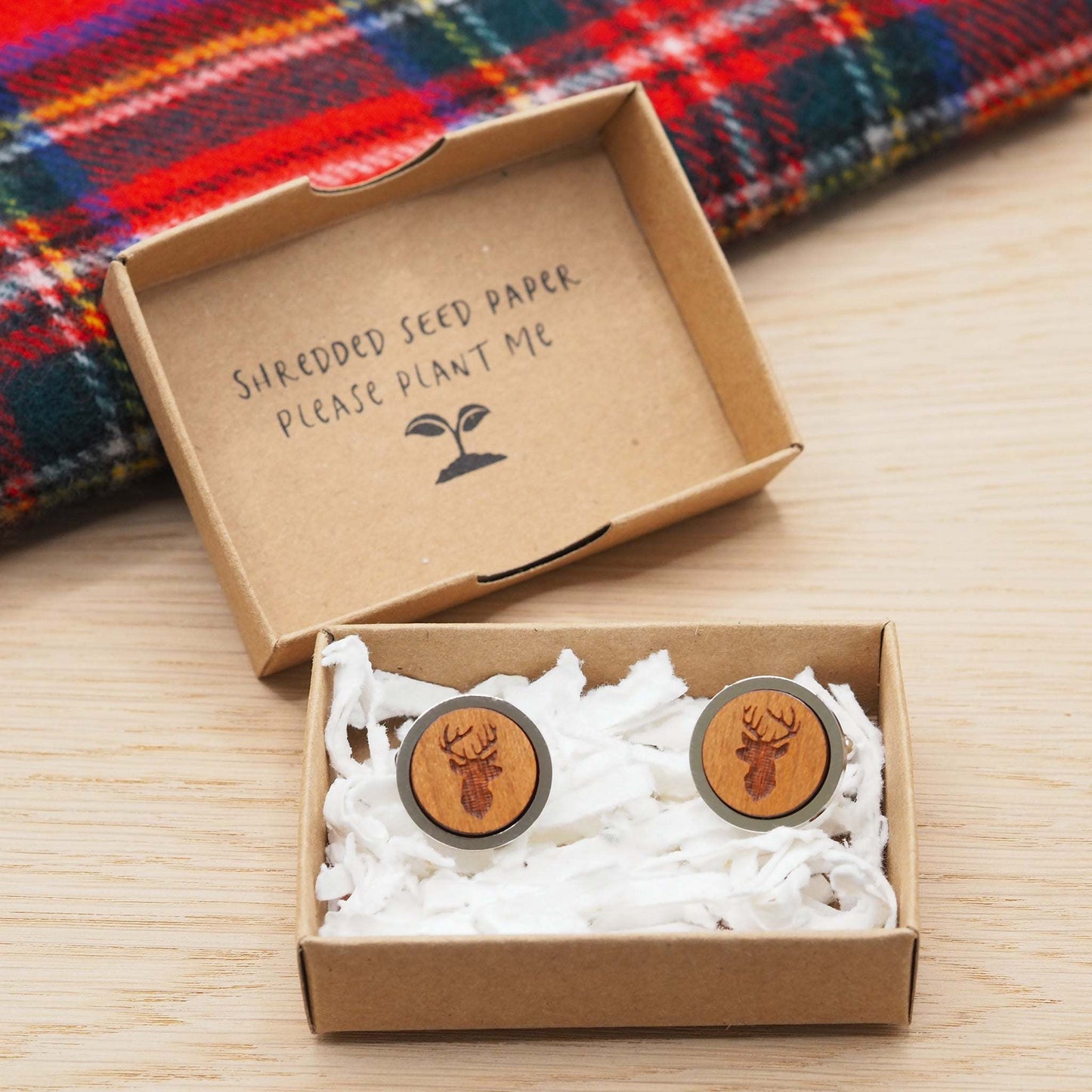 Stags head wooden cufflinks in eco-friendly packaging with Scottish plaid background.