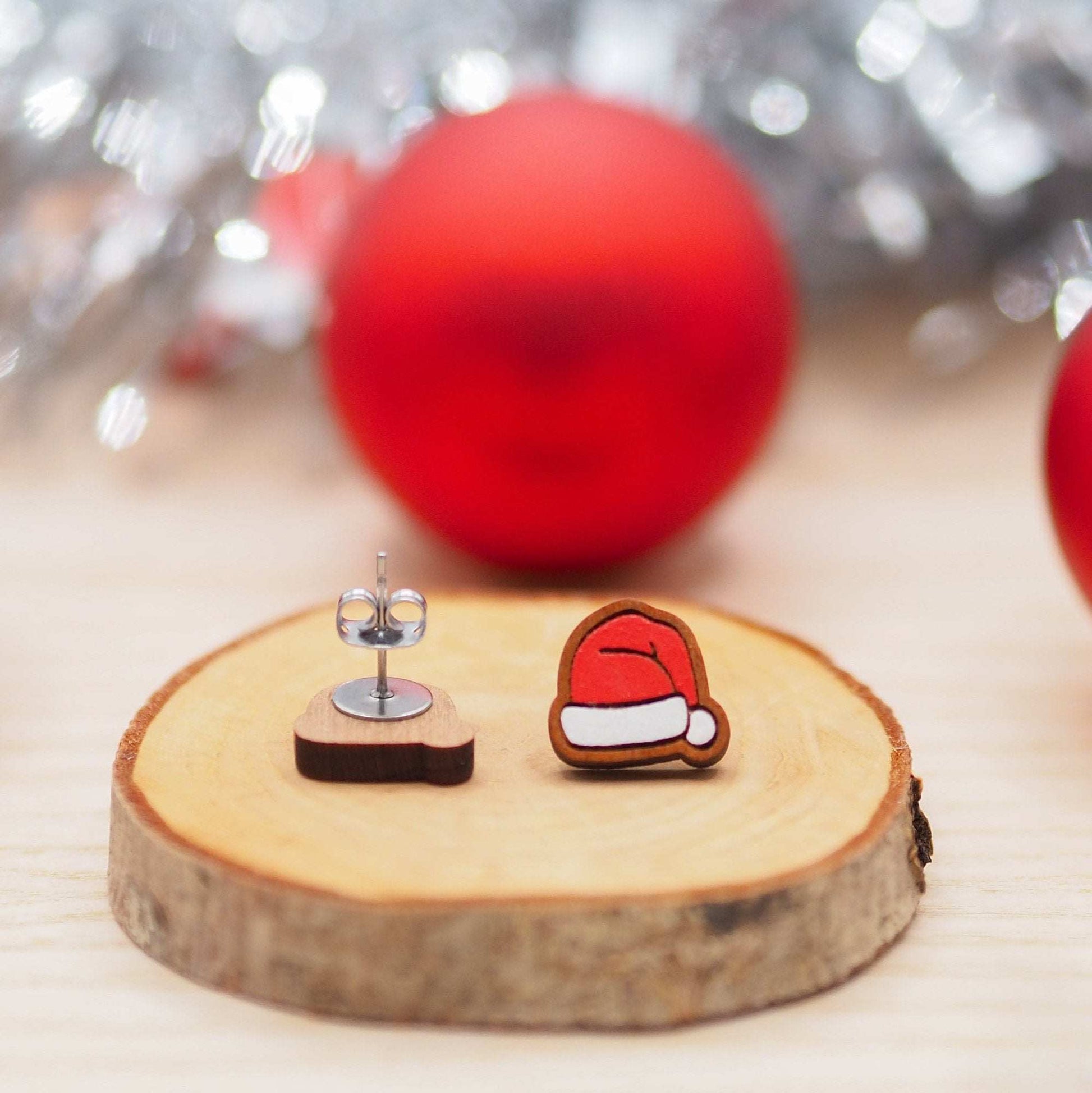 Sustainable cherry wood Santa hat studs with surgical steel posts, eco-friendly gift box.