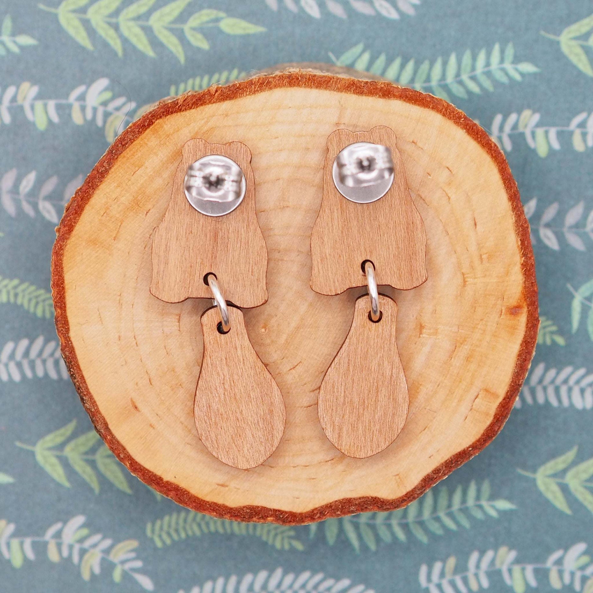 Beaver stud earrings made of cherry wood with sterling silver and surgical steel posts, presented on a wooden backdrop.