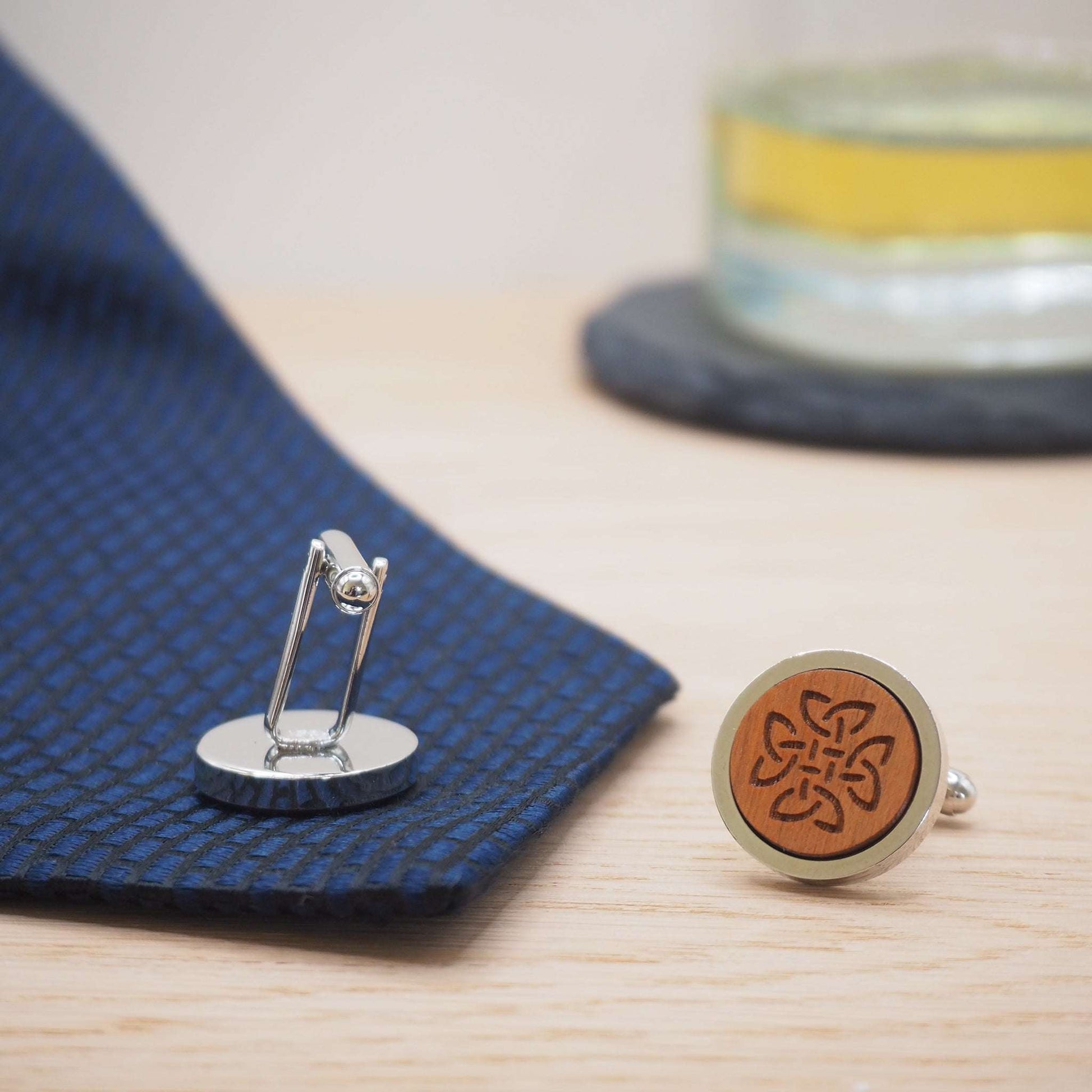 Celtic knot wooden cufflinks engraved on cherry wood with rhodium bezels, displayed with blue fabric and eco-friendly packaging.