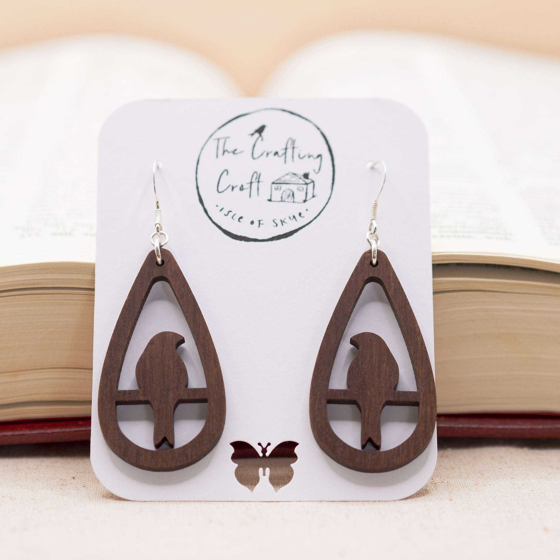 Teardrop bird drop earrings in walnut wood with sterling silver hooks displayed on eco-friendly packaging.