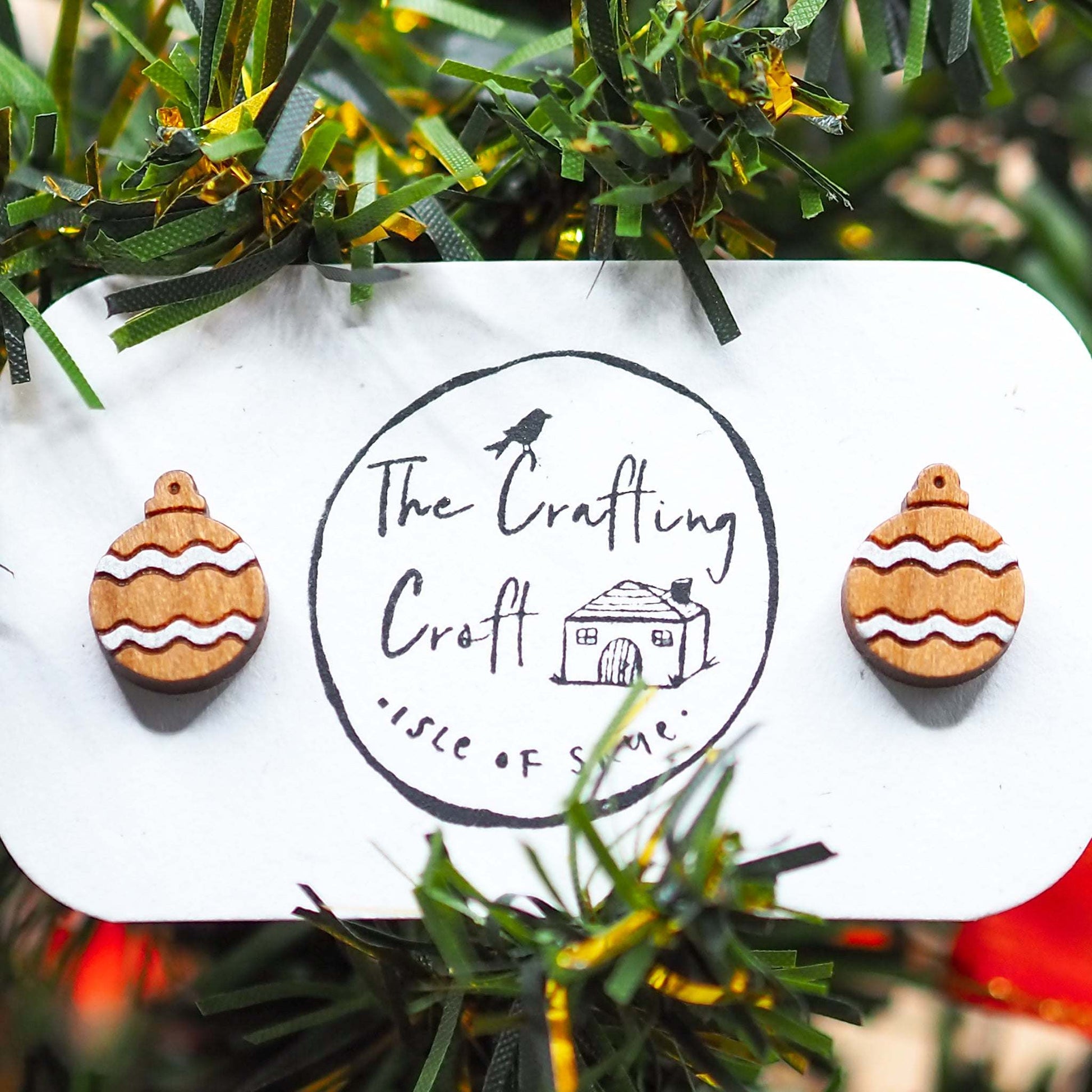 Silver Christmas bauble earrings made of cherry wood with silver pattern on a display card.