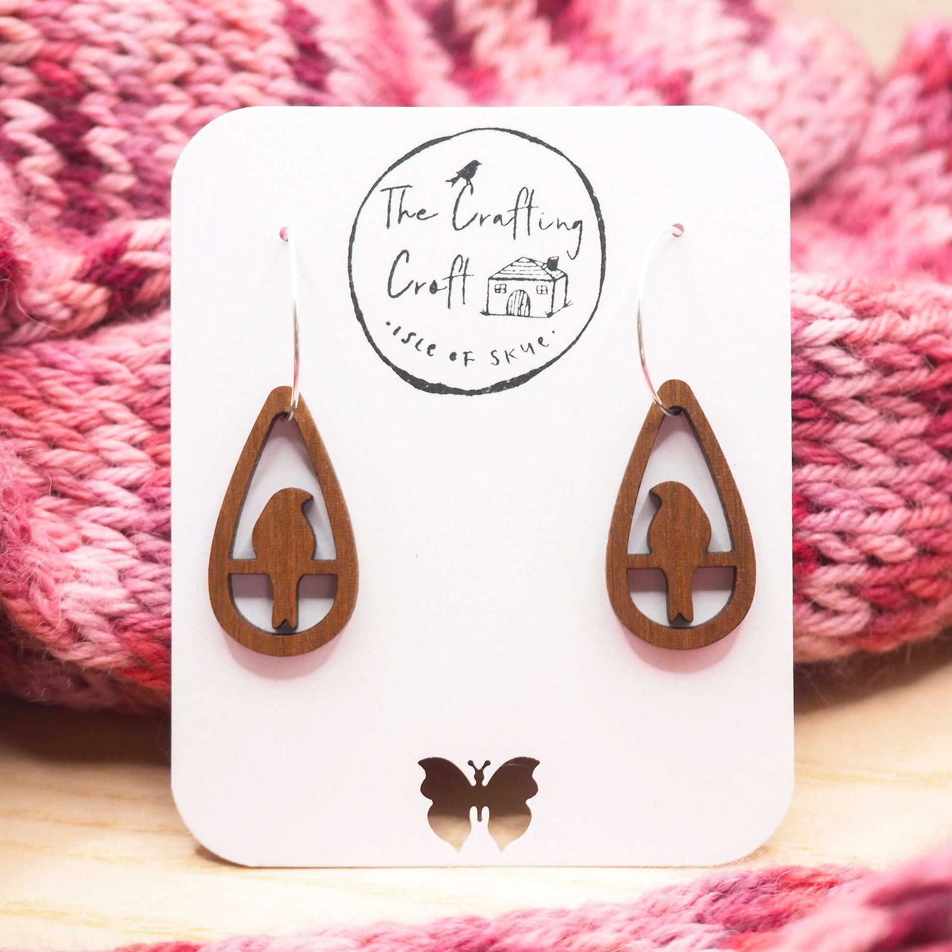 Perching bird teardrop hoop earrings with walnut wood and sterling silver on display card.