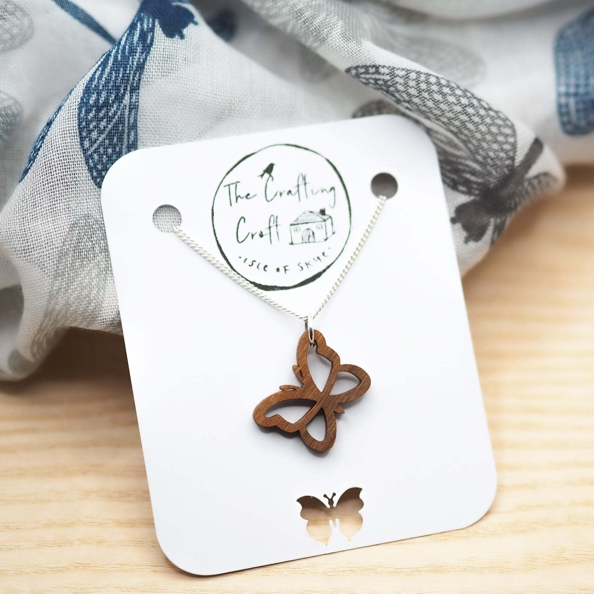 Delicate butterfly outline necklace made from laser-cut walnut wood, with a recycled sterling silver chain. Eco-friendly packaging for gifting.