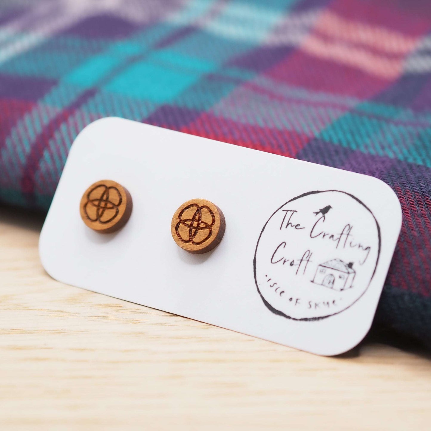 Celtic flower knot stud earrings in cherry wood on card with tartan background