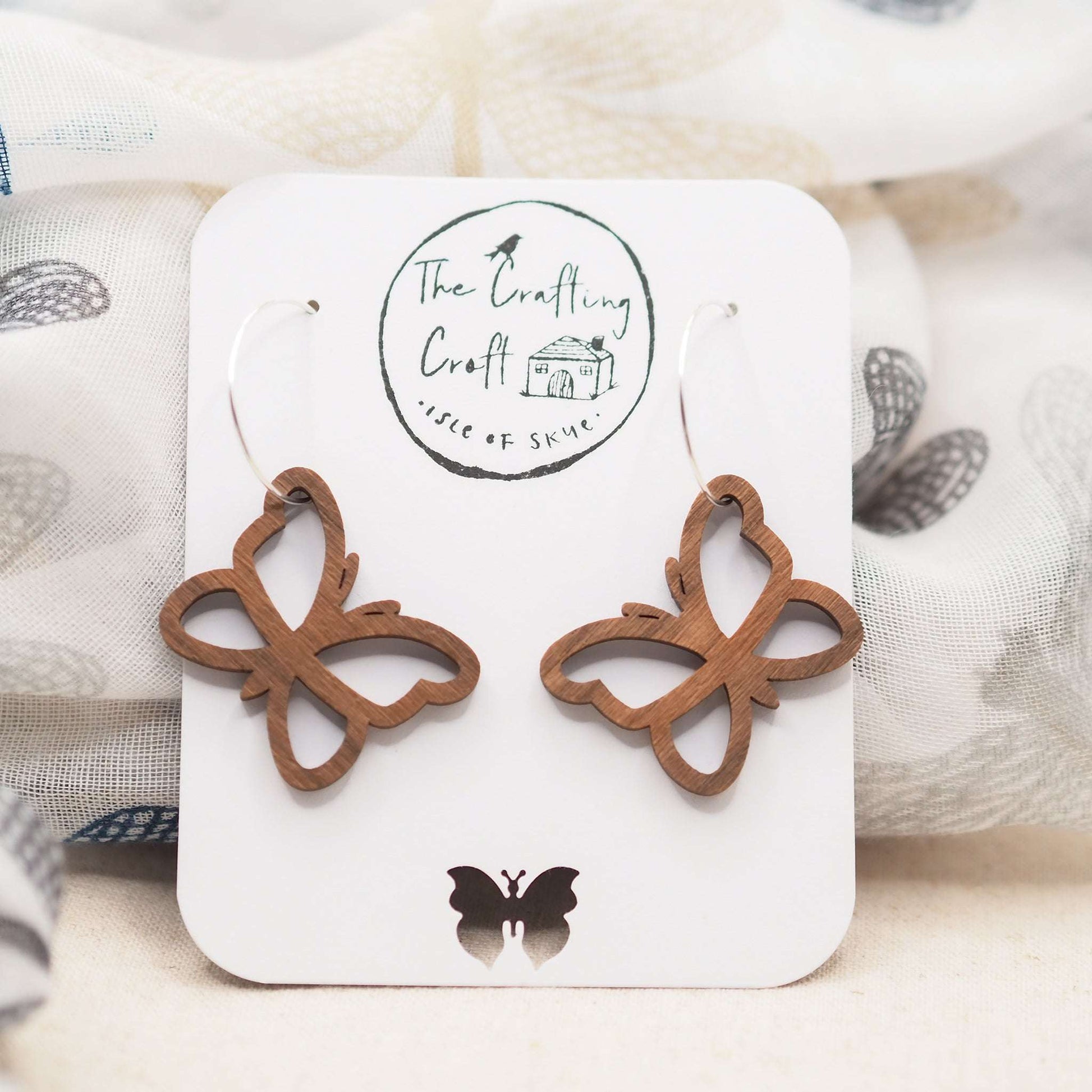Butterfly outline hoop earrings made from walnut wood with sterling silver hoops.