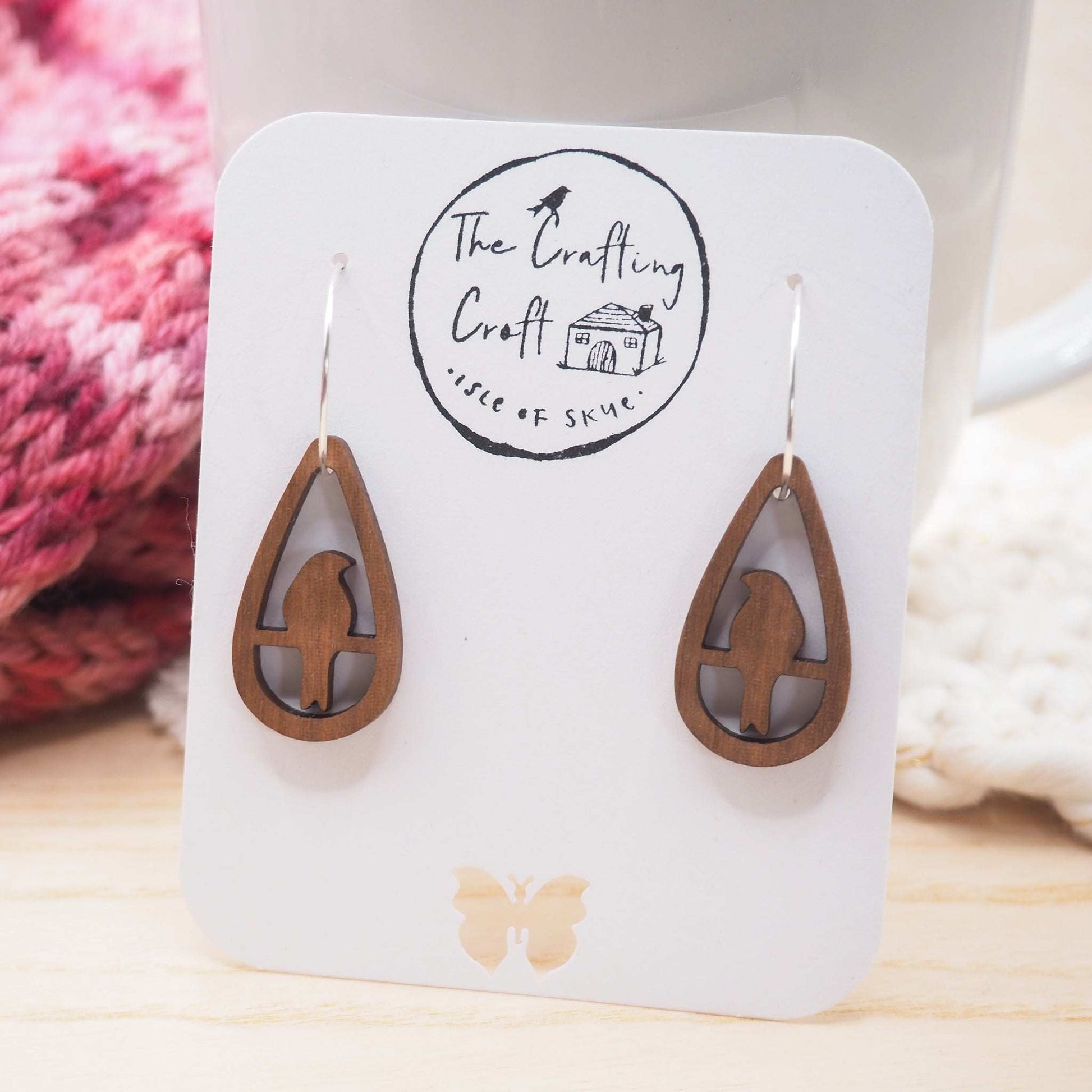 Perching bird teardrop hoop earrings made from walnut wood with sterling silver hoops displayed on a card.
