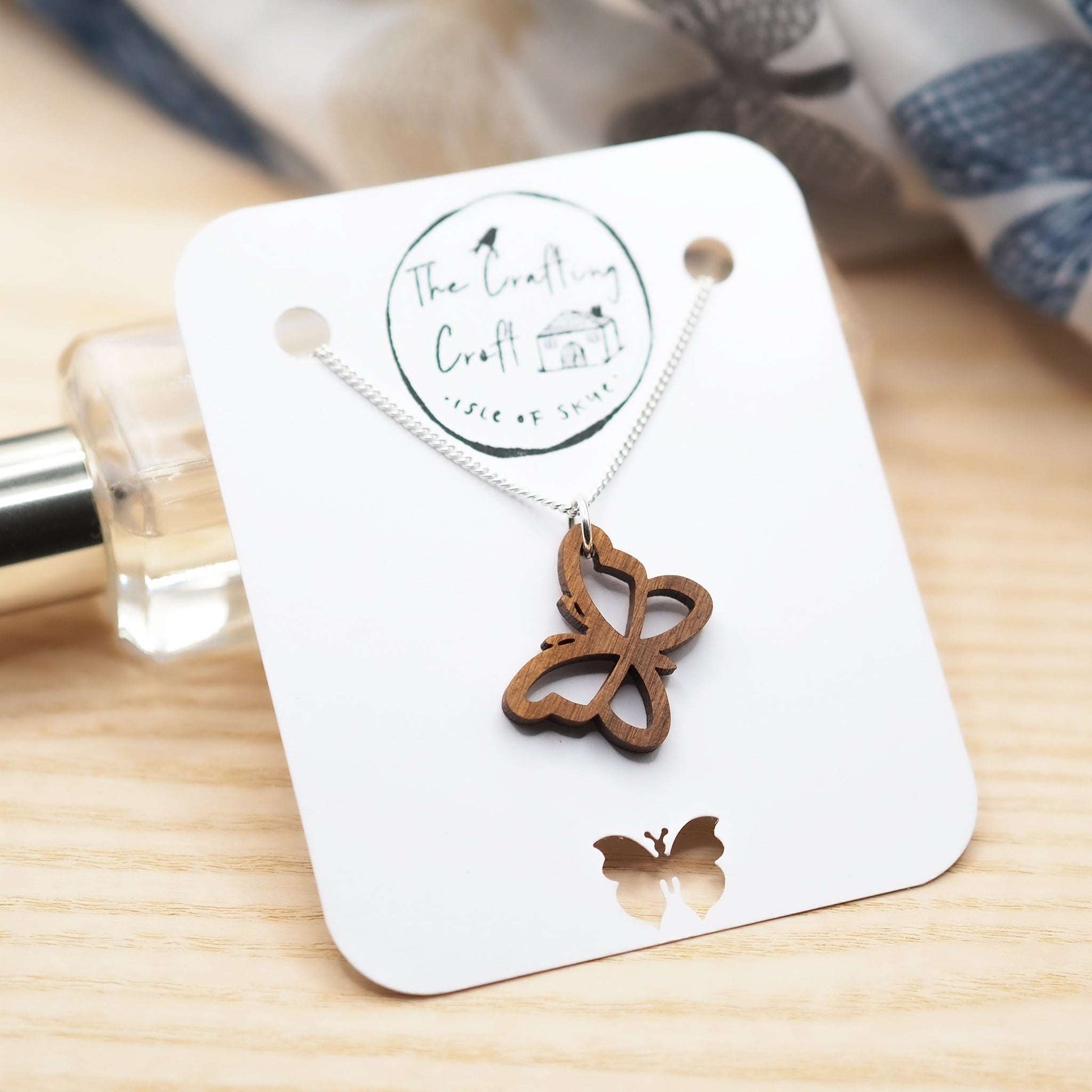 Sustainably sourced walnut butterfly outline necklace on recycled sterling silver chain.