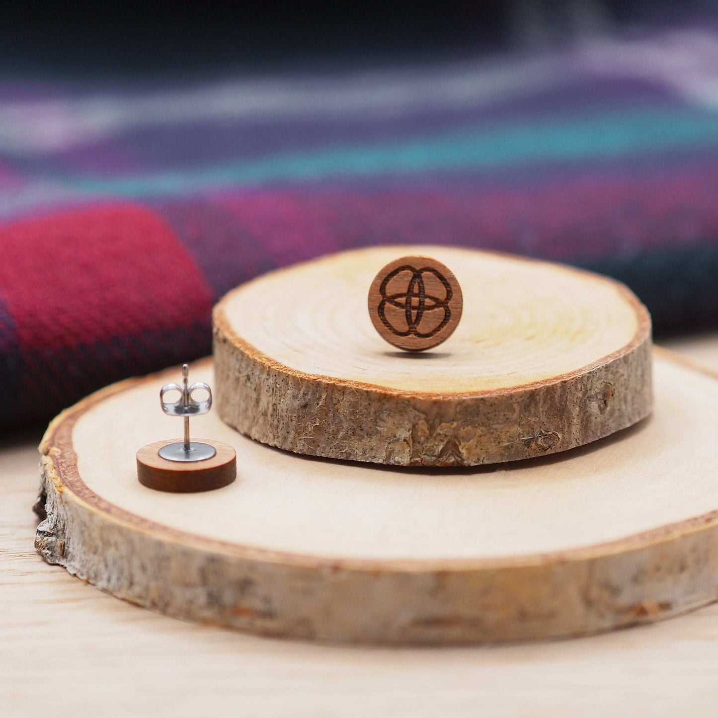 Solid cherry wood Celtic flower knot stud earrings on wooden display.