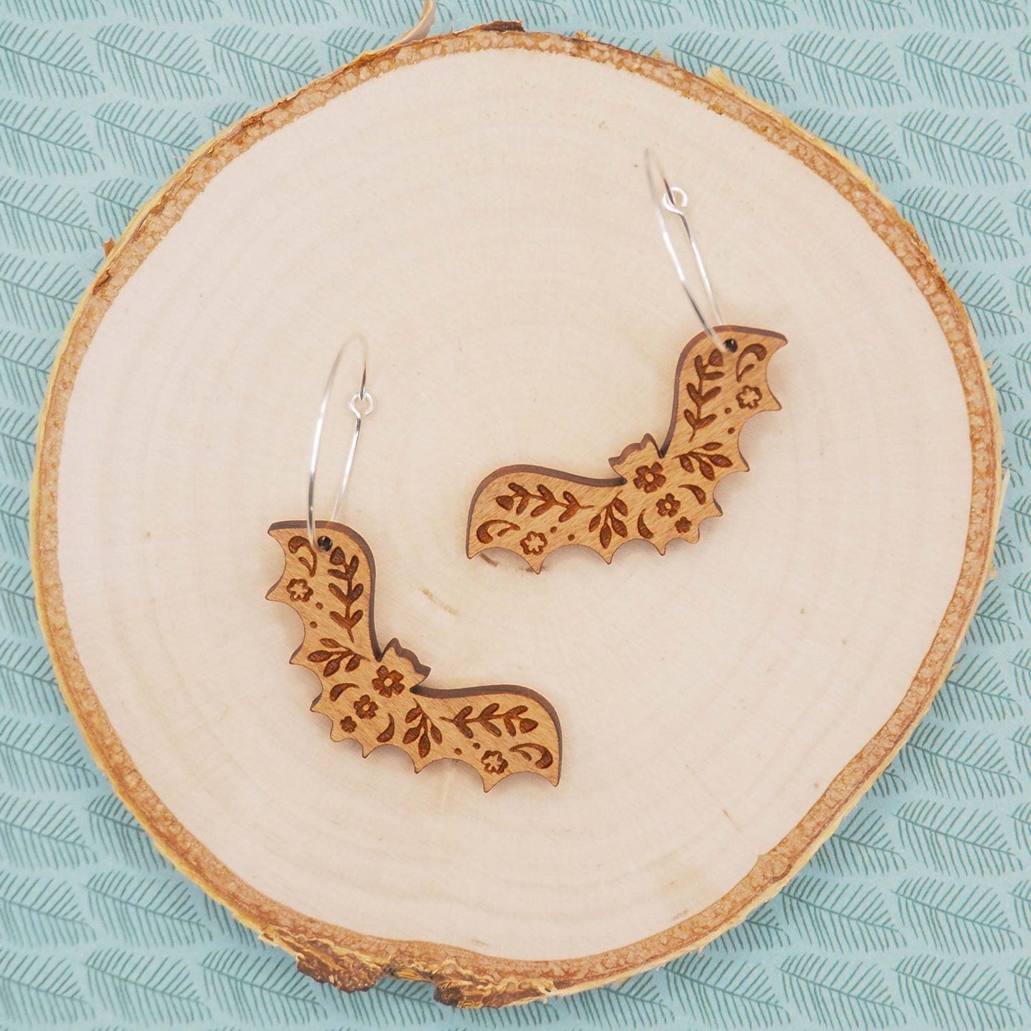 Bat hoop earrings made from cherry wood with sterling silver hoops, featuring intricate patterns.