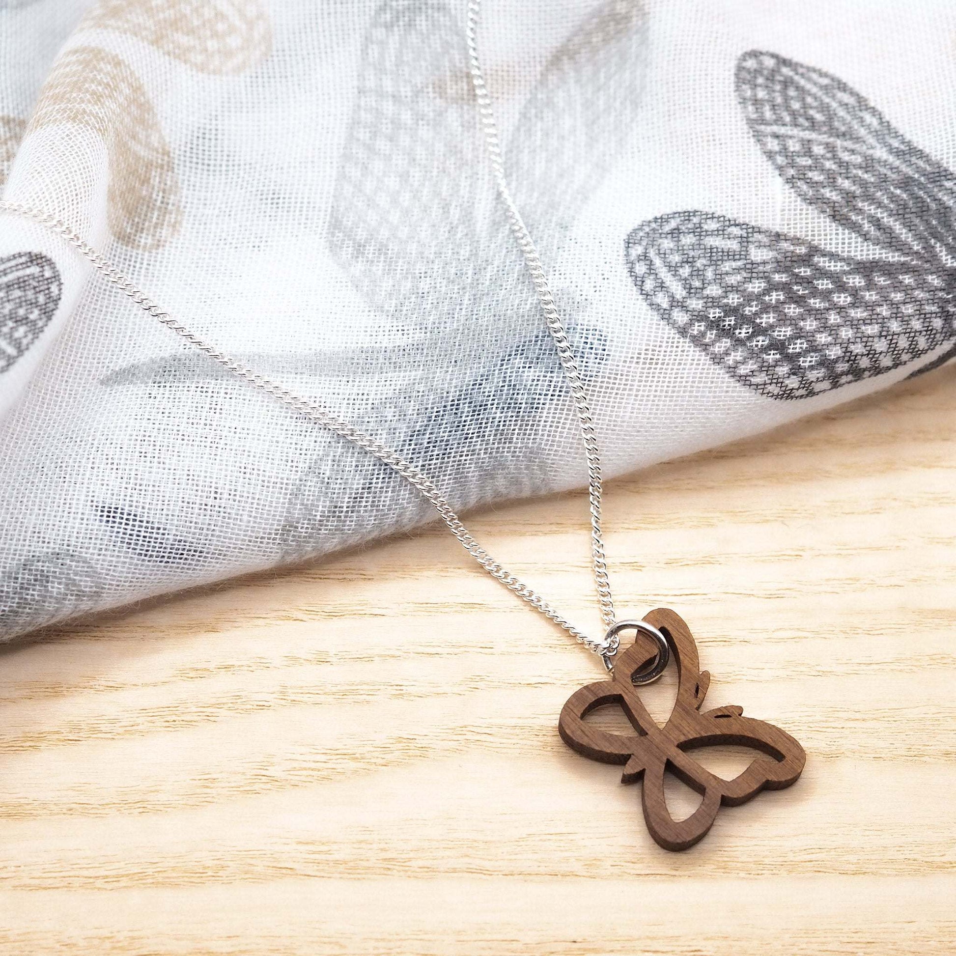 Butterfly outline necklace on 18 inch recycled sterling silver chain displayed on fabric.