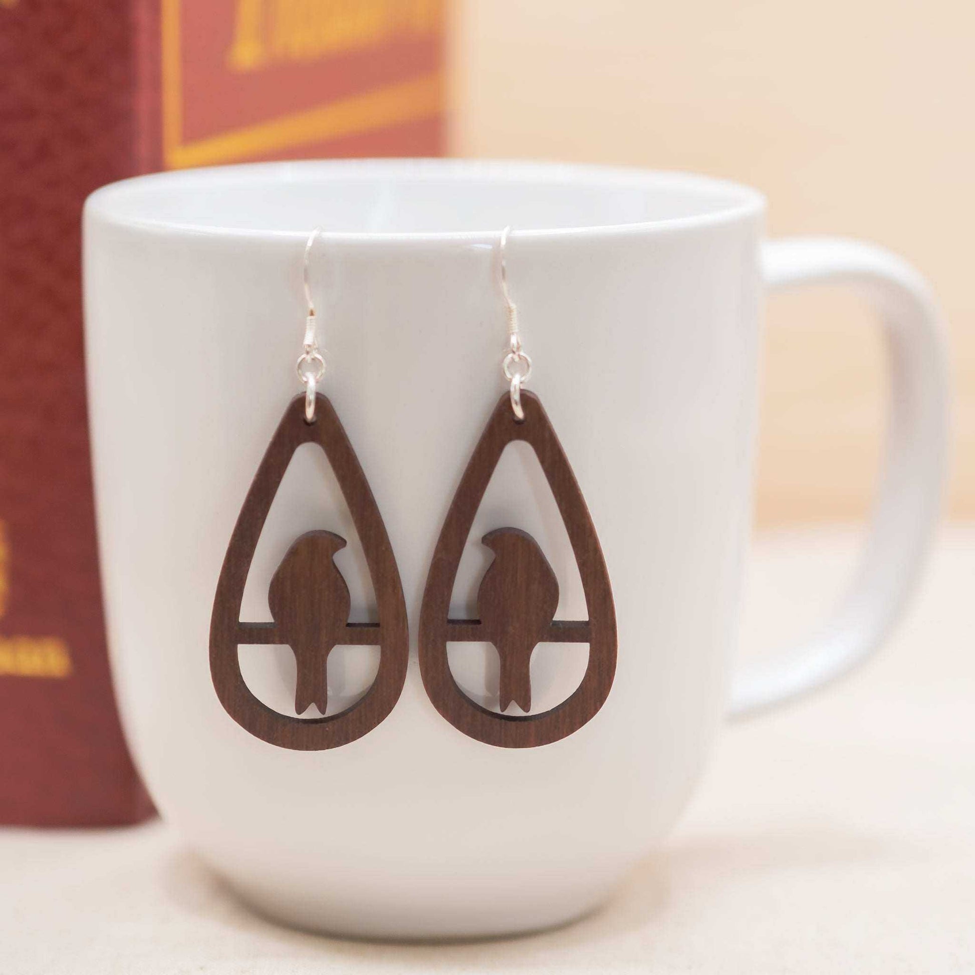 Sustainable walnut teardrop bird drop earrings with sterling silver hooks.