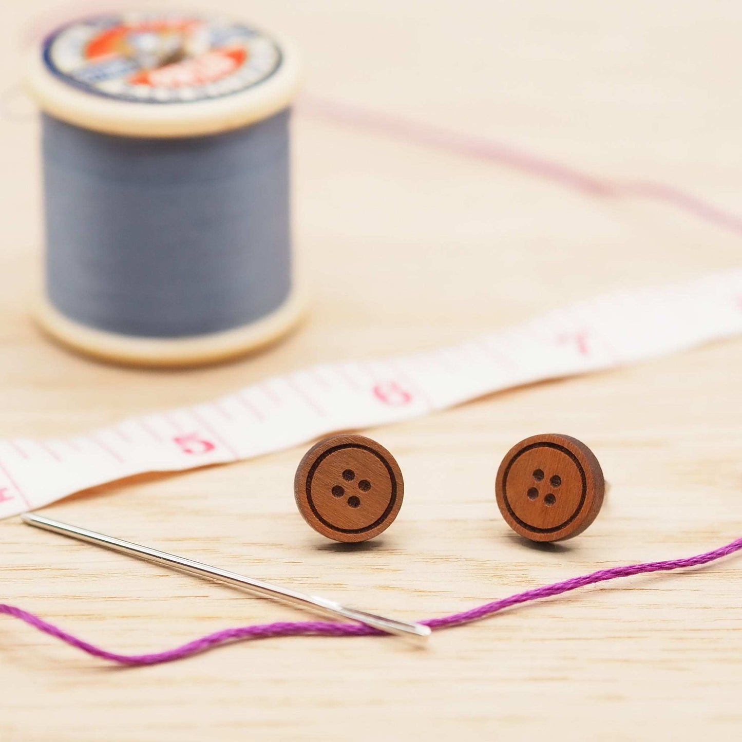 Cherry wood button stud earrings with surgical steel backs, shown with sewing accessories.