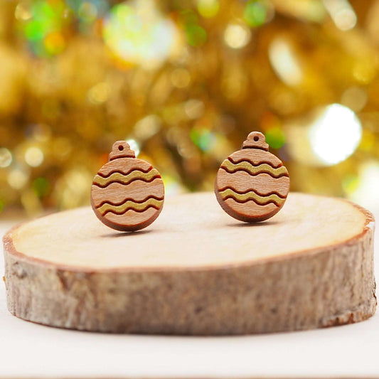 Festive woodcut gold Christmas bauble earrings on display with a golden bokeh background.