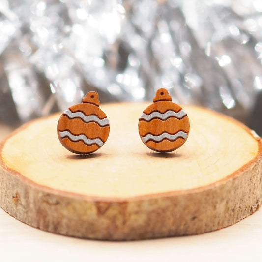 Silver Christmas bauble earrings on wood, featuring hand-painted silver pattern with surgical steel posts.
