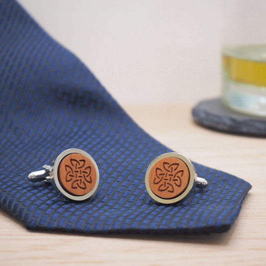 Celtic knot wooden cufflinks engraved on cherry wood with silver tone rhodium bezels displayed on a blue tie.