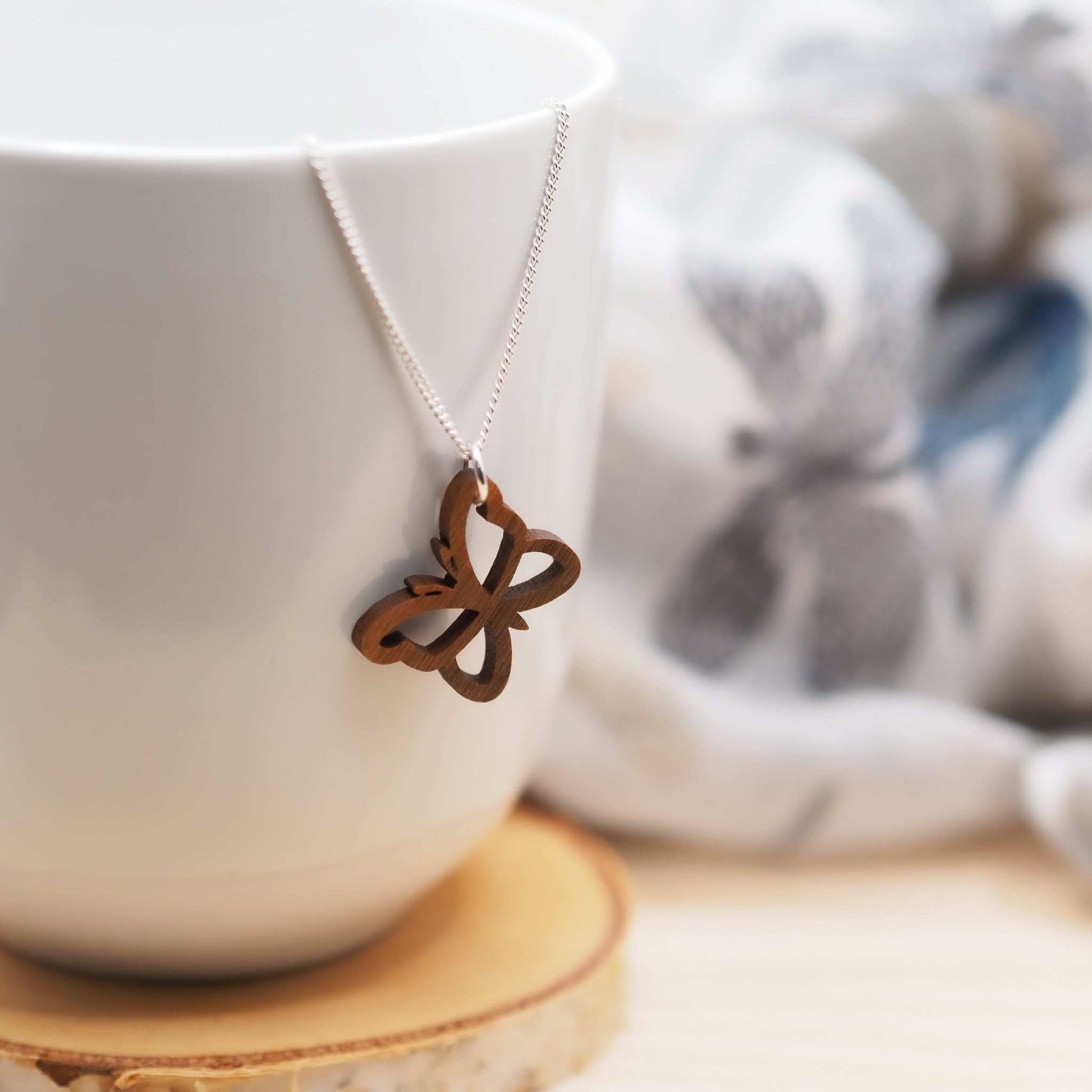 Delicate butterfly outline necklace made from walnut wood with a recycled sterling silver chain.
