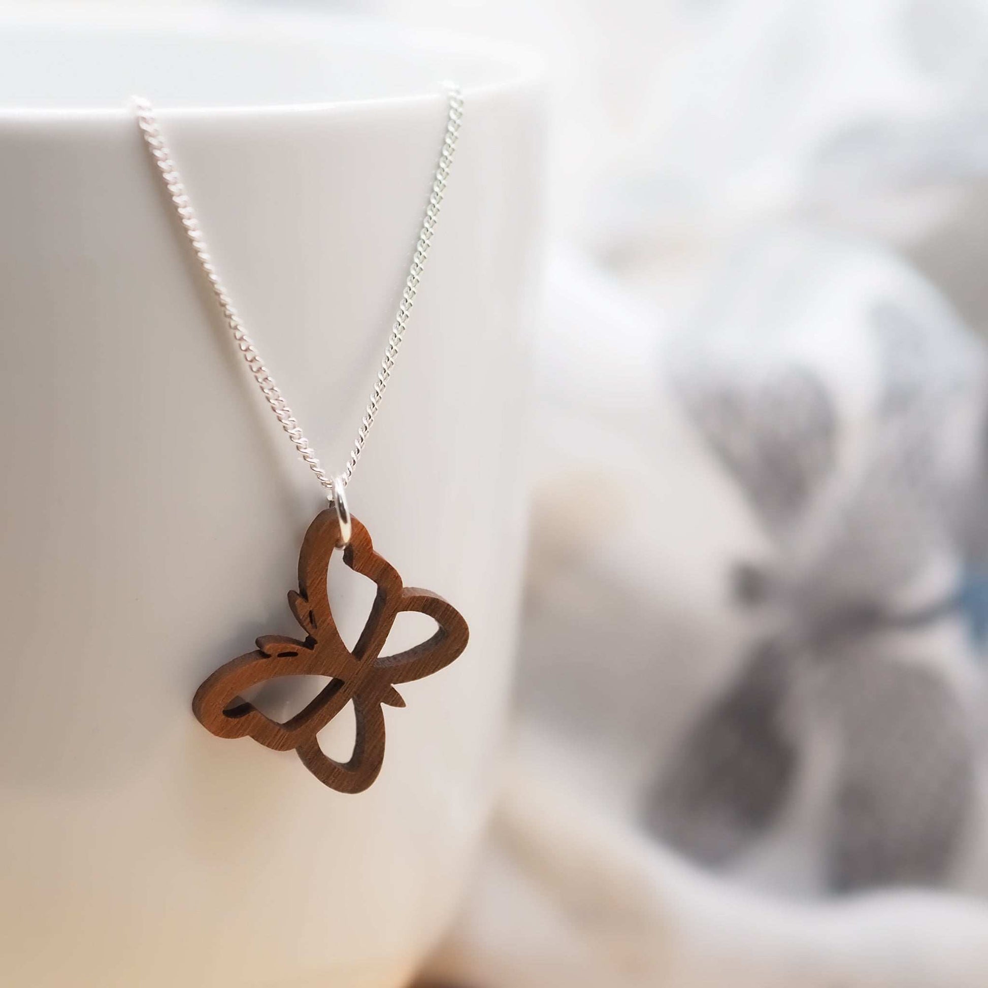Butterfly outline necklace with walnut wood pendant on sterling silver chain.