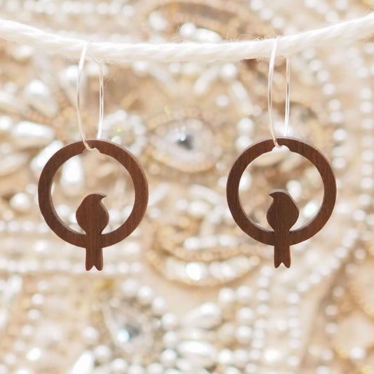 Perching bird hoop earrings made from sustainable walnut wood with sterling silver hoops.