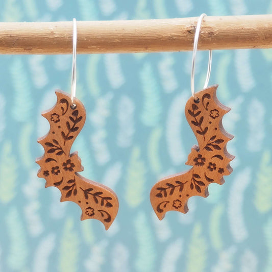 Bat hoop earrings made from cherry wood with intricate patterns and sterling silver hoops.