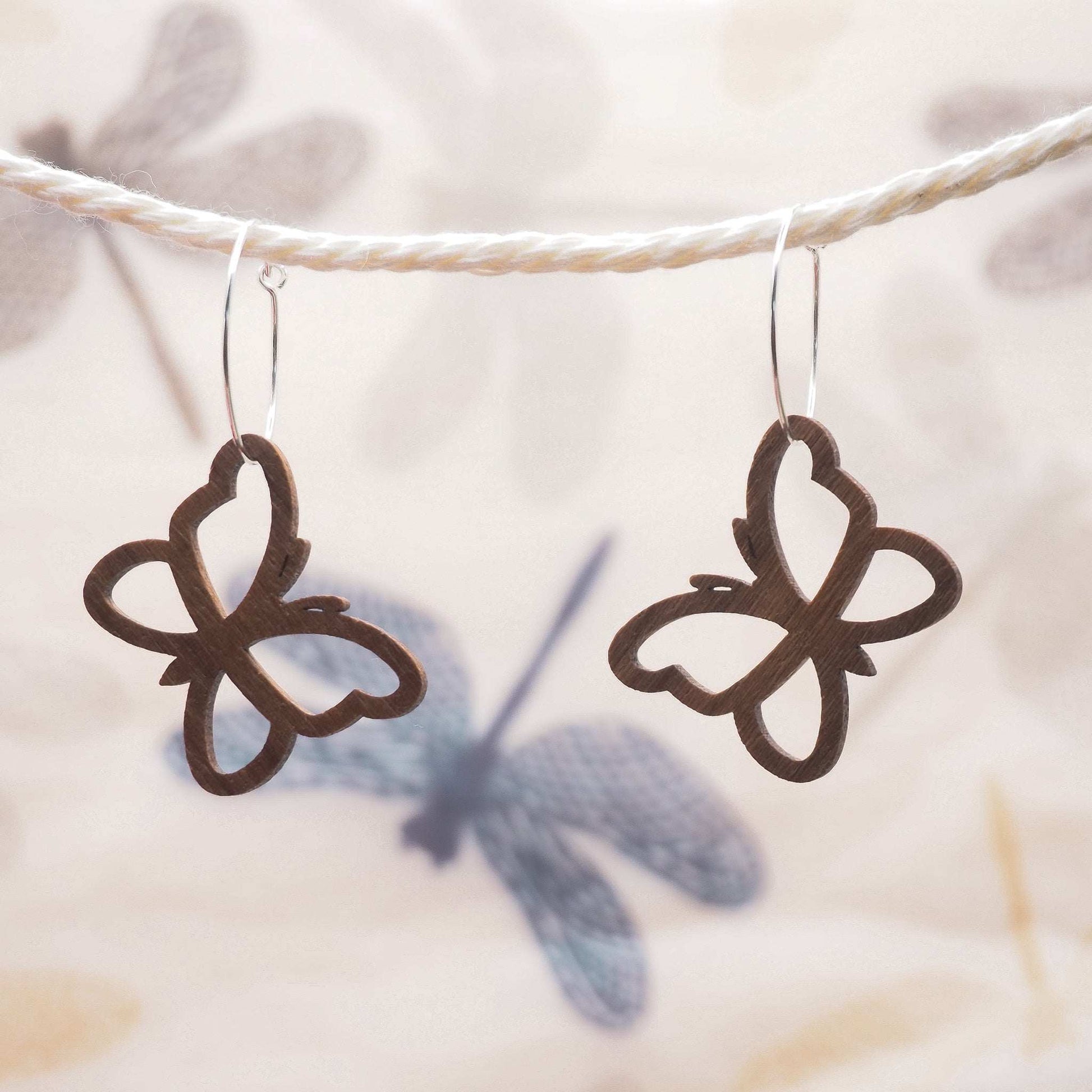 Butterfly outline hoop earrings made from walnut wood and sterling silver.