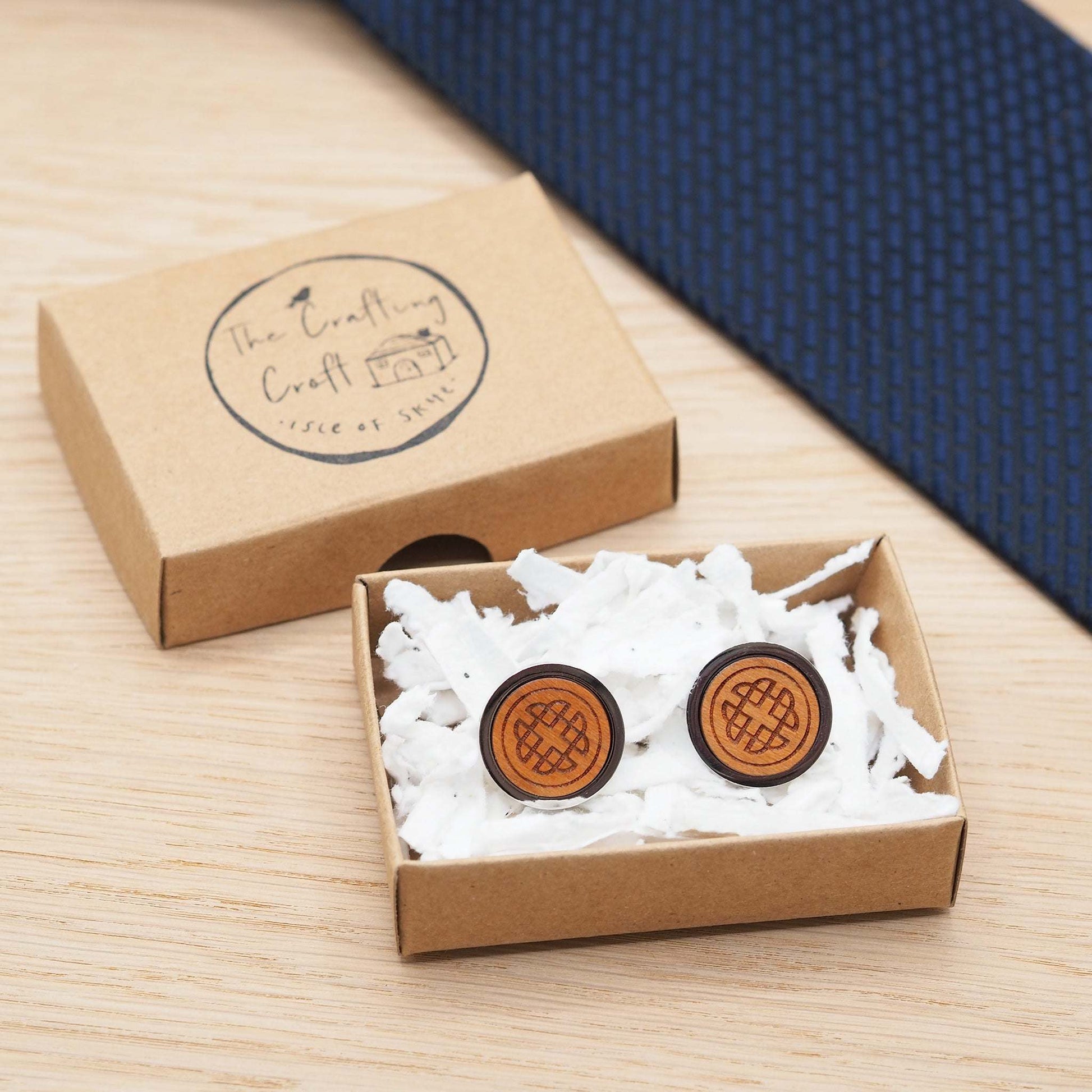 Intricate Celtic knot wooden cufflinks in eco-friendly box on a wooden surface.