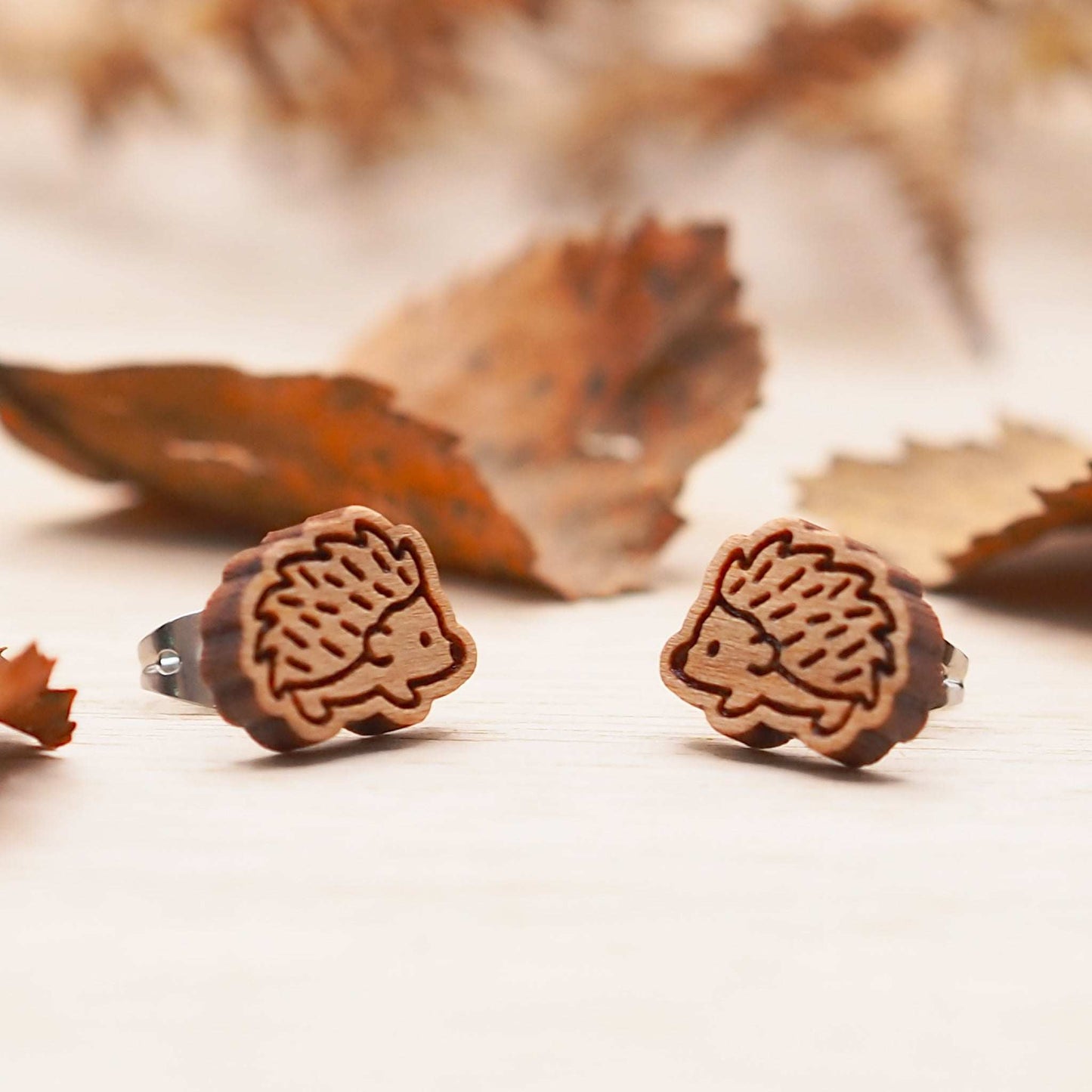 Wooden hedgehog stud earrings with engraved design, made from solid cherry wood and mounted on surgical steel backs.