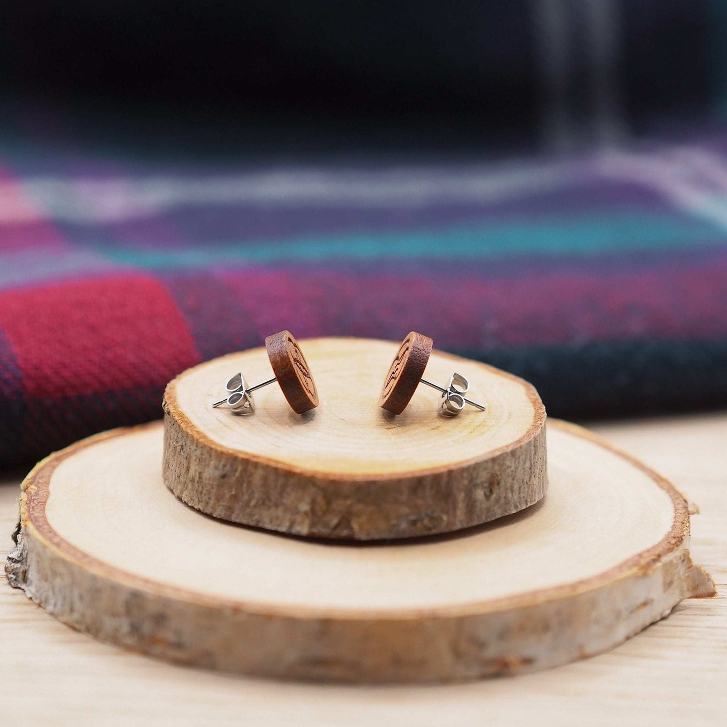 Celtic flower knot stud earrings made of cherry wood and surgical steel, displayed on wood slices.