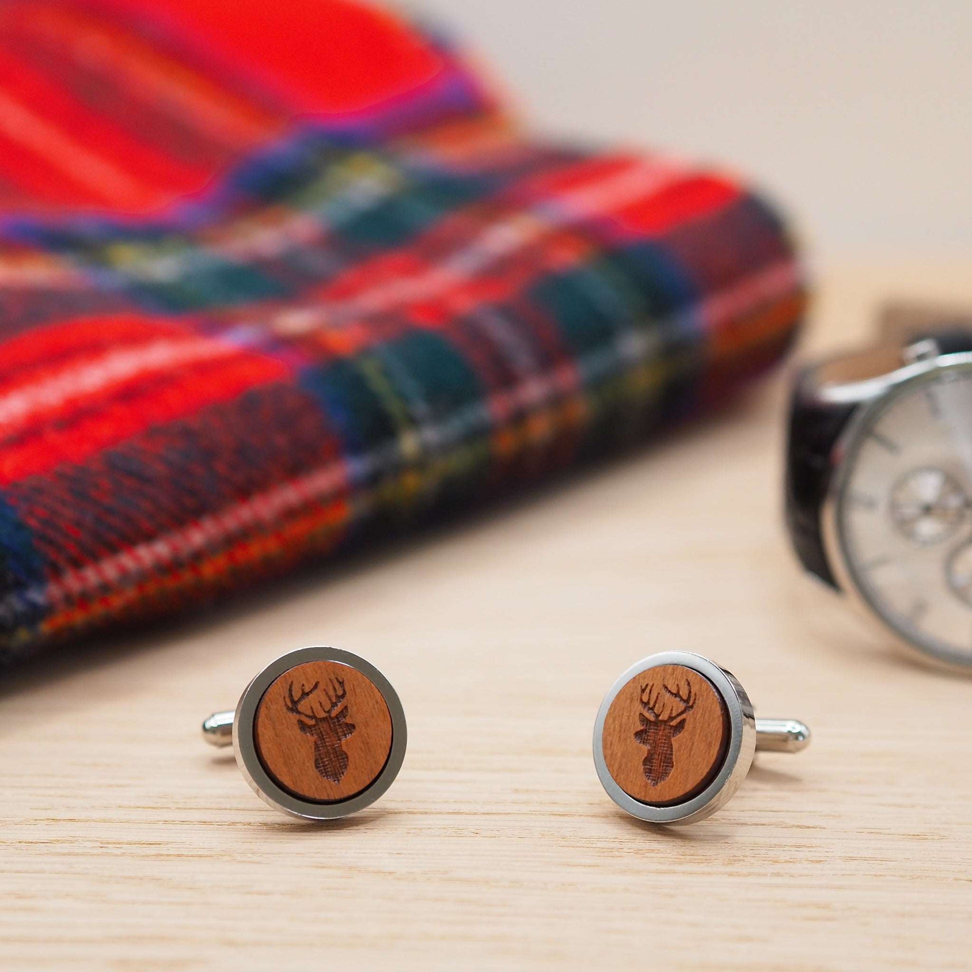 Stags head wooden cufflinks on wood surface, featuring engraved stag design in cherry wood with silver-tone rhodium bezel, eco-friendly packaging.